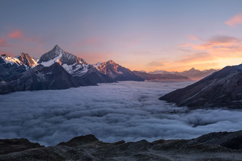 A calm mountain lake at sunrise with mist rising over still water.